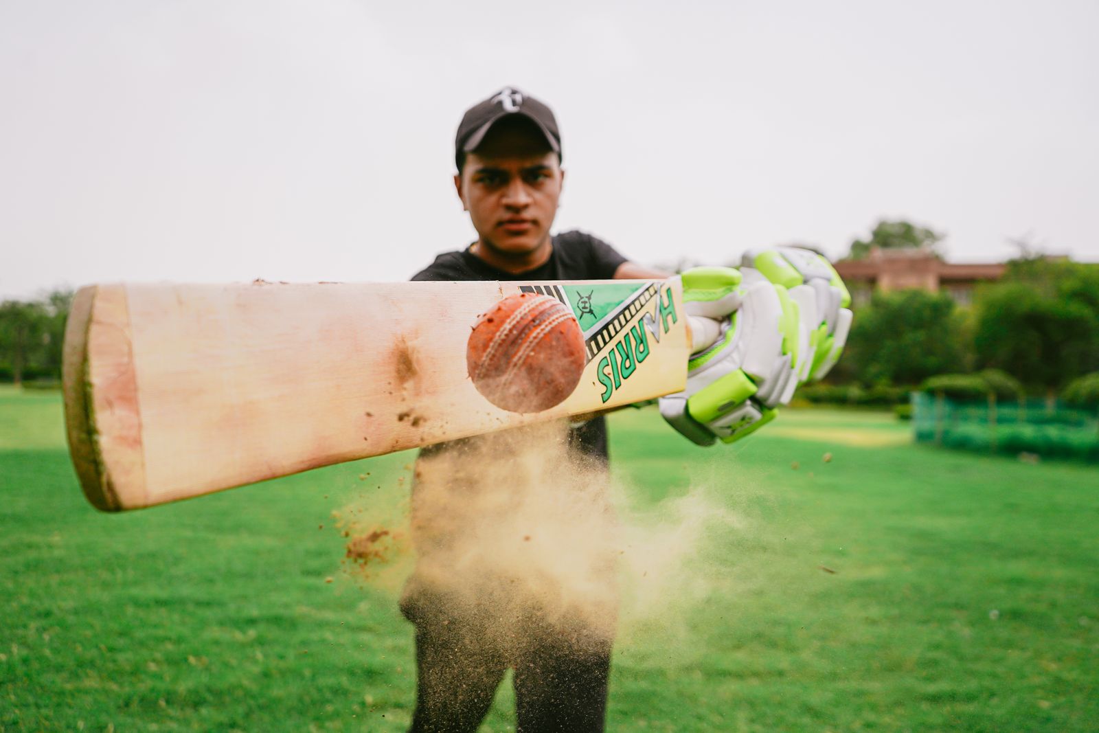 Cricketer playing a shot, dust rising off the pitch